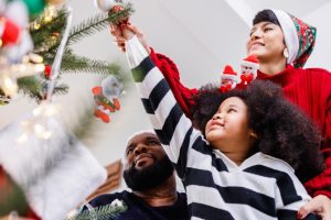 child helps parent decorate christmas tree